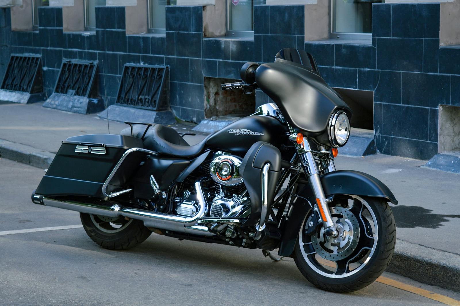 Classic black motorcycle parked beside a building in the city, showcasing its vintage design.