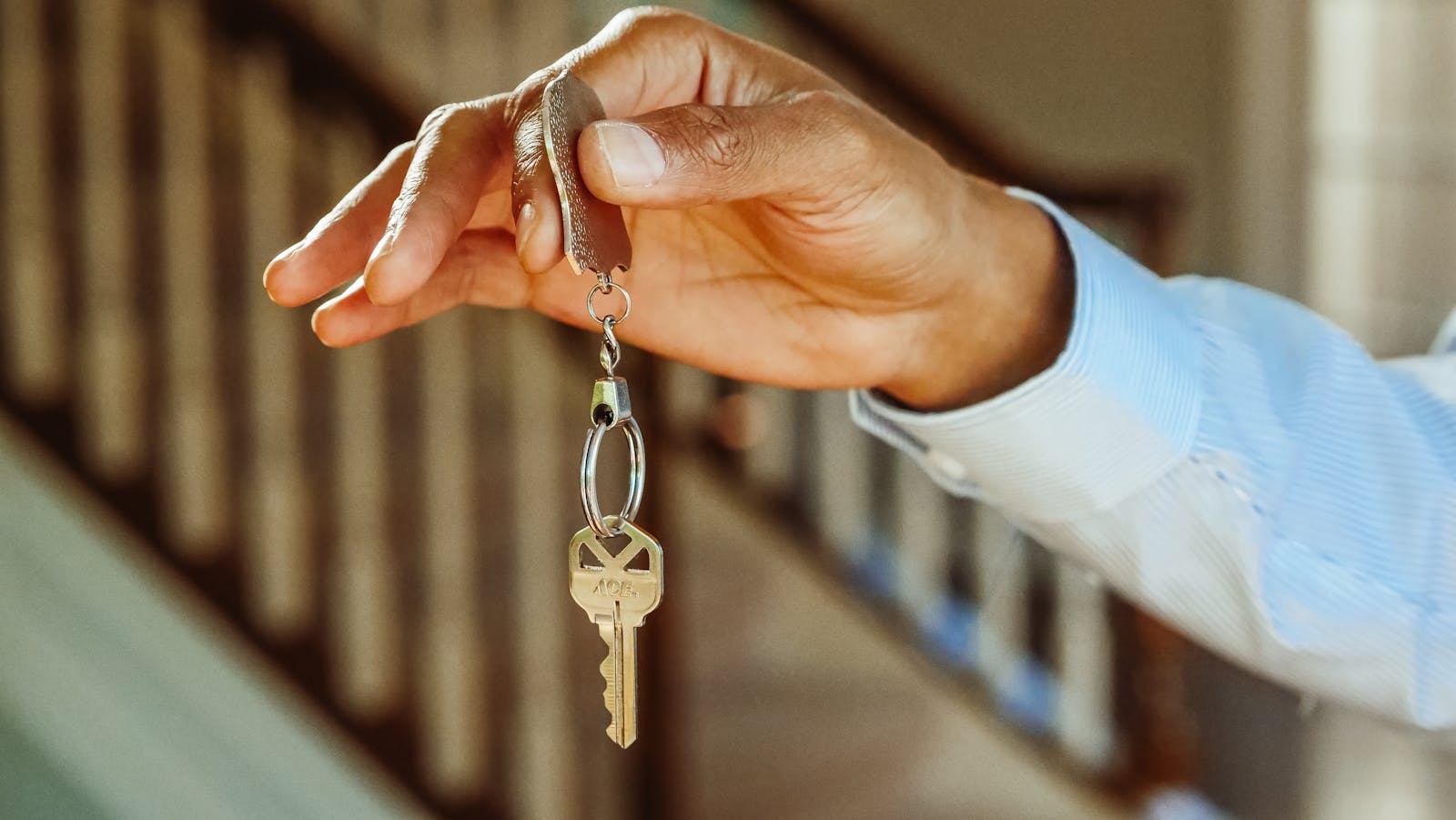 renters, a close-up shot of a hand holding a house key, indicating new ownership or rental.